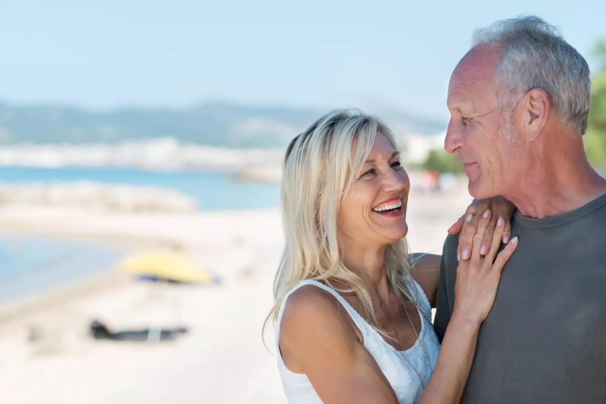 Couple senior souriant sur une plage, célébrant leurs 40 ans de mariage. Une scène symbolique des noces d’émeraude, entre tendresse, amour durable et bonheur partagé.